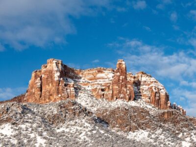 white snow on red rock forms against a blue sky.