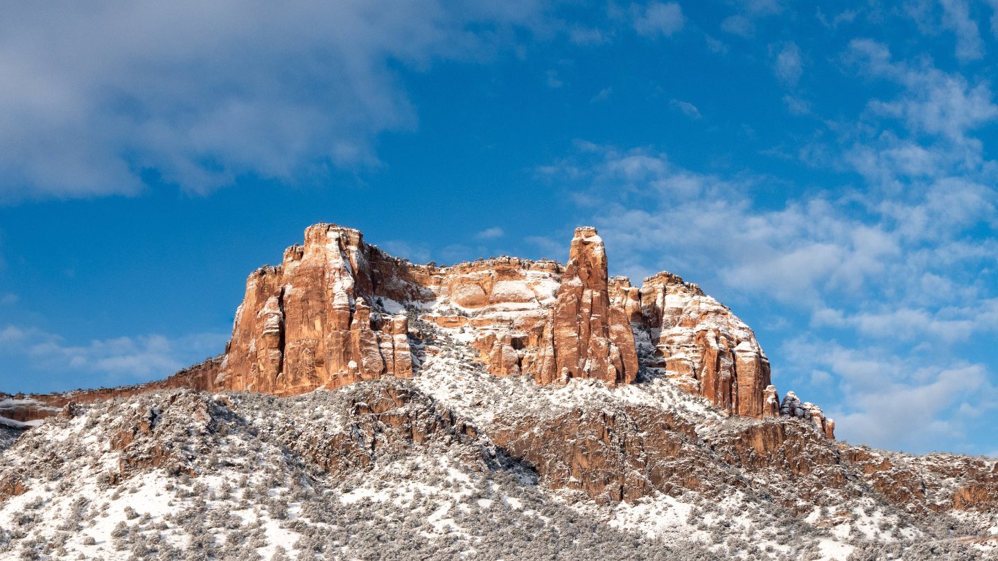 white snow on red rock forms against a blue sky.